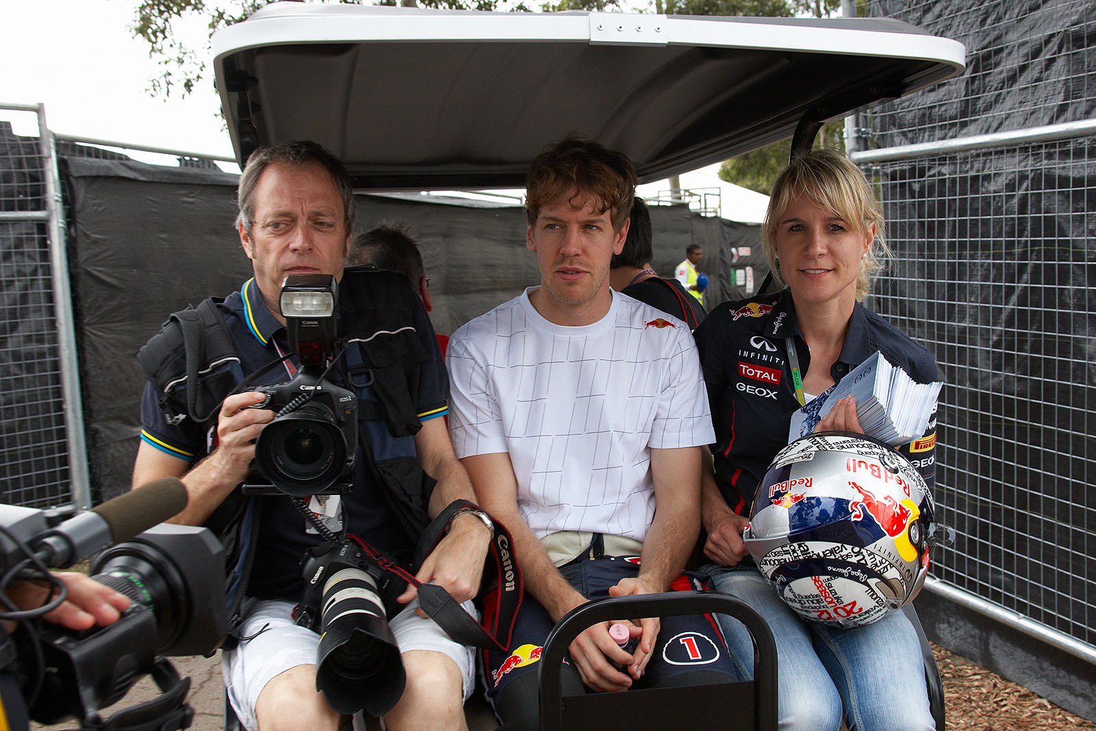 Making his way to drivers presentation on a golf caddy, Sebastian Vettel sits between Getty photographer Mark Thompson and his personal assistant Britta Roeske