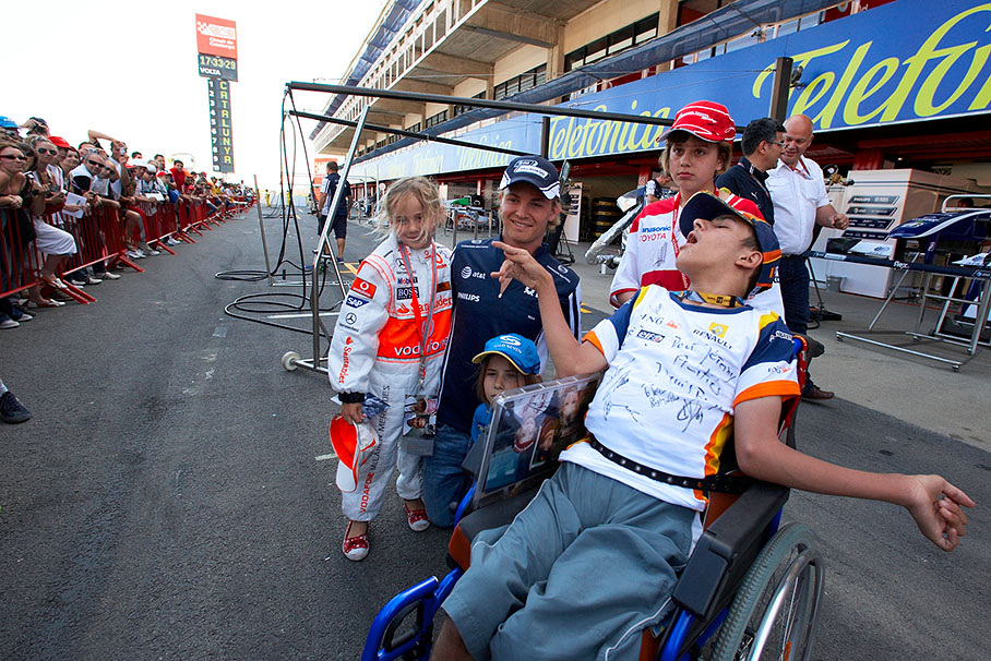 Williams' Nico Rosberg poses with children for a souvenir photo at thursday pit walkabout