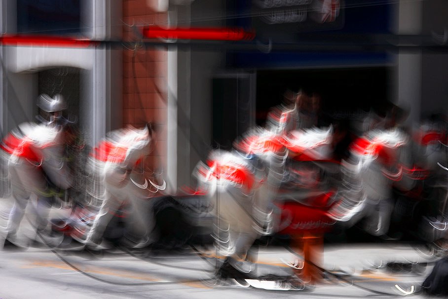 The McLaren pit crew pushes Kovalainen backward after his Q3 stint