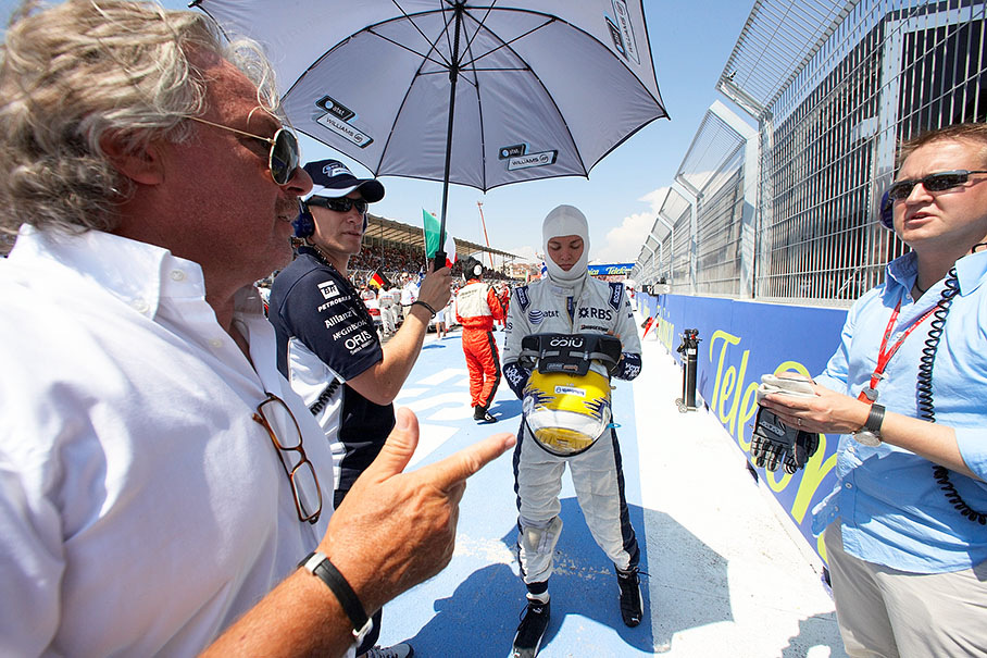 While Oliver holds the parasol, papa Keke Rosberg awaits son Nico on the grid