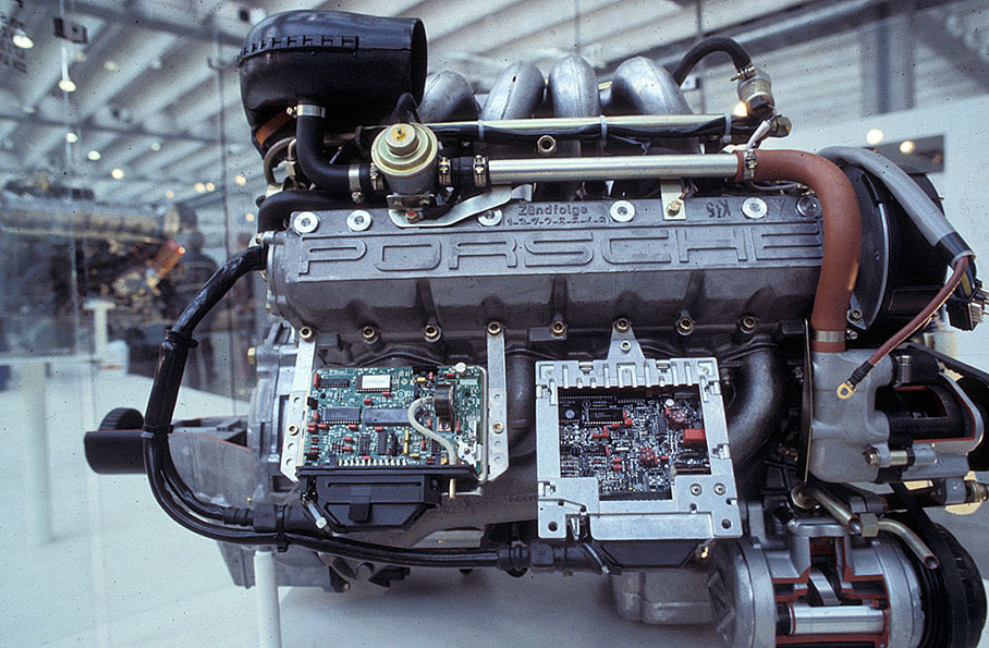 A display shows a Porsche engine and its electronic components