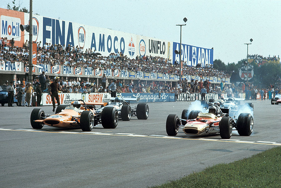 At the start of the Italian GP 1969, polesitter Jochen Rindt lets the wheels of his Lotus-Cosworth 49B spin besides Denny Hulme on McLaren-Cosworth M7A