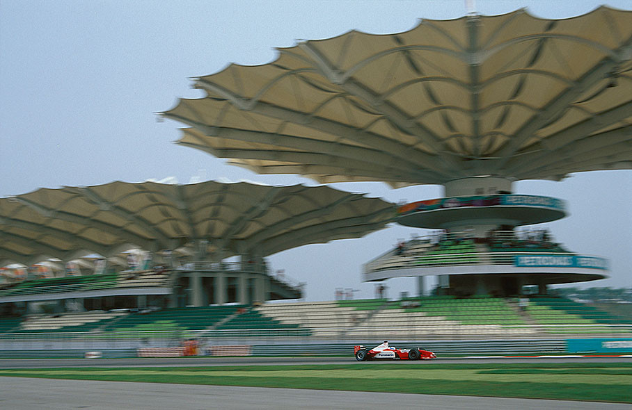 Mika Salo passing the empty grandstands during a practice session