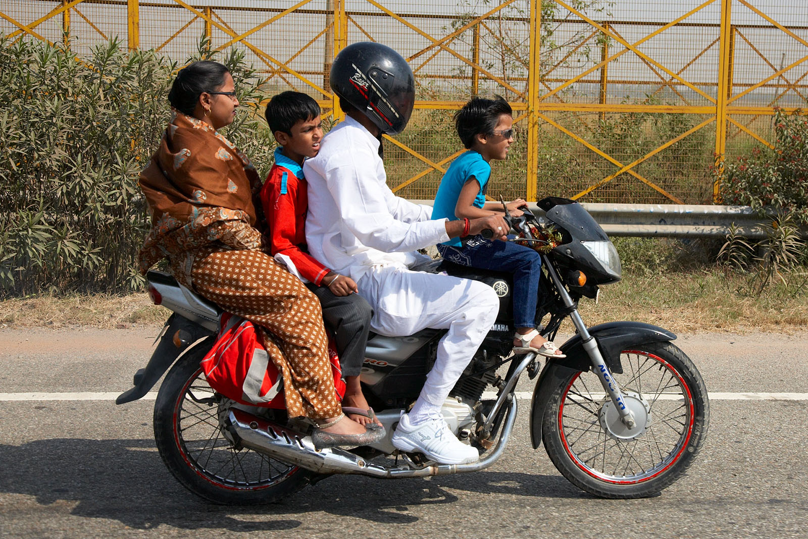 A family is traveling on a motorbike near the circuit