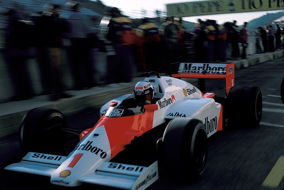 Alain Prost, McLaren, passing a crowded pit wall