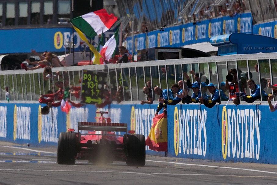 Cheering crews with the respective national flags bending over the pitwall