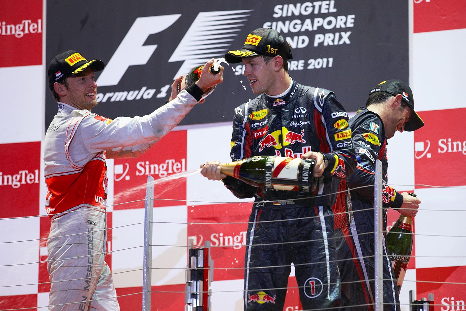 Red Bull Racing's race winner Sebastian Vettel gives a champagne shower to second placed Jenson Button of McLaren during podium ceremony