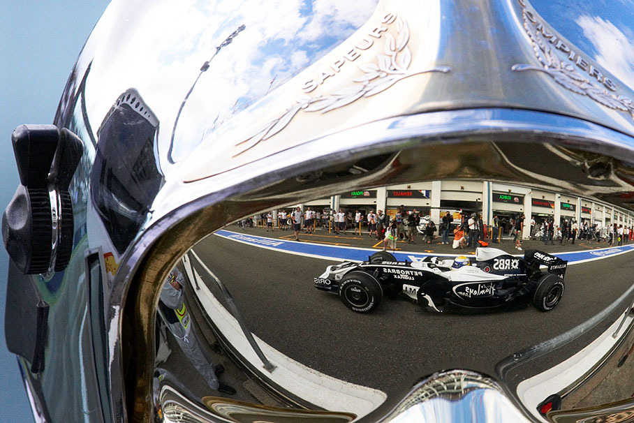 Williams driver Nico Rosberg, as a reflection in a firemarshal's helmet visor