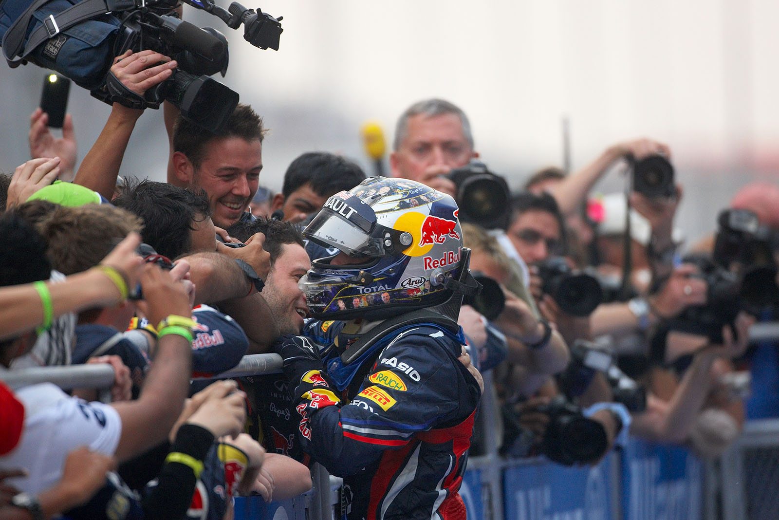 Race winner Sebastian Vettel of Red Bull Racing celebrates with his team at the parc ferme fencing