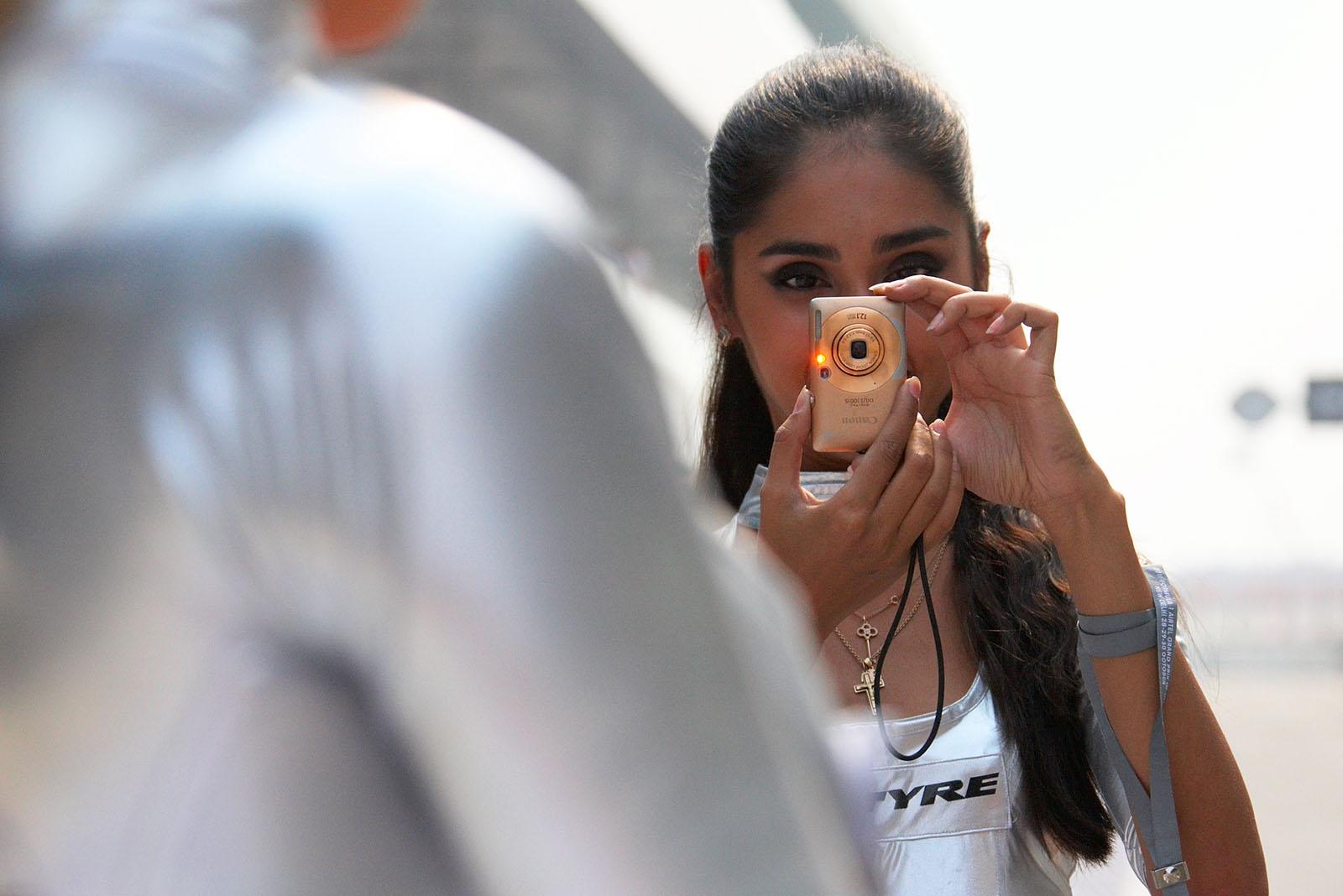 Russian tyre promotion beauties take photographs of each other in the pitlane