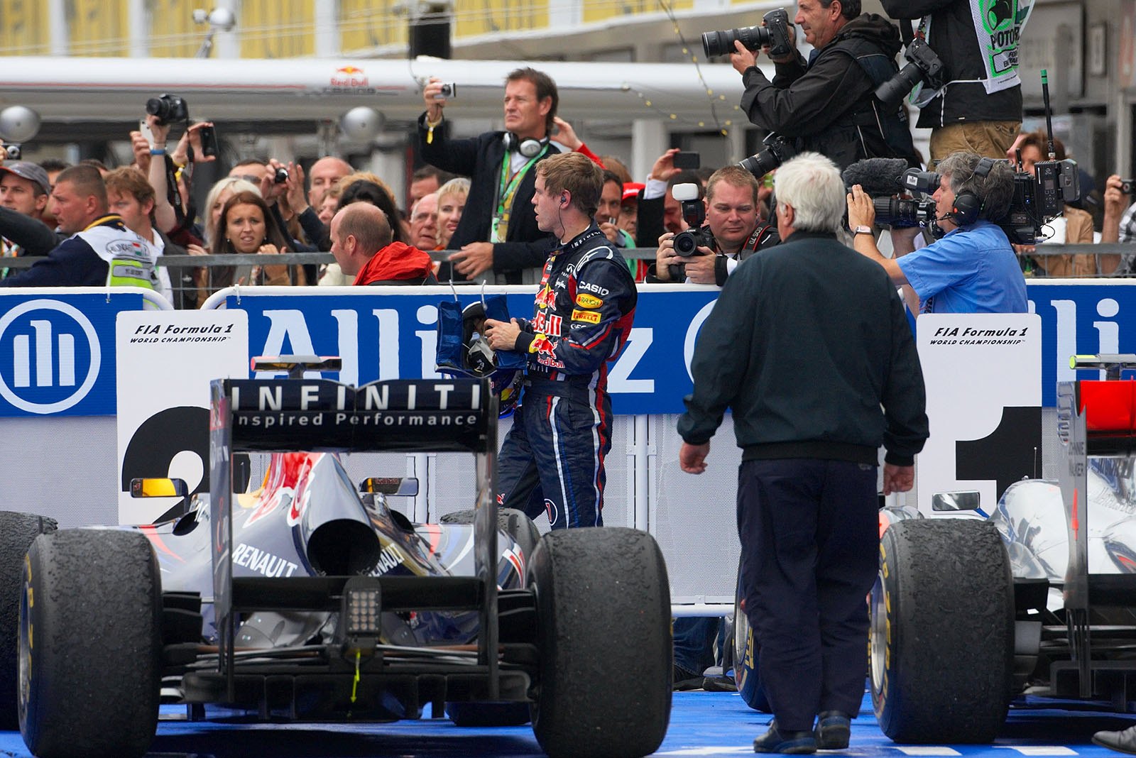 Second placed Sebastian Vettel watches race winner Jenson Button of McLaren celebrating with his mechanics besides parc ferme