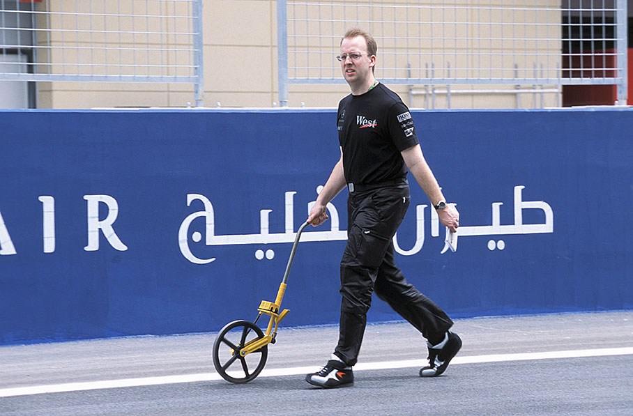 A McLaren mechanic measures the track length