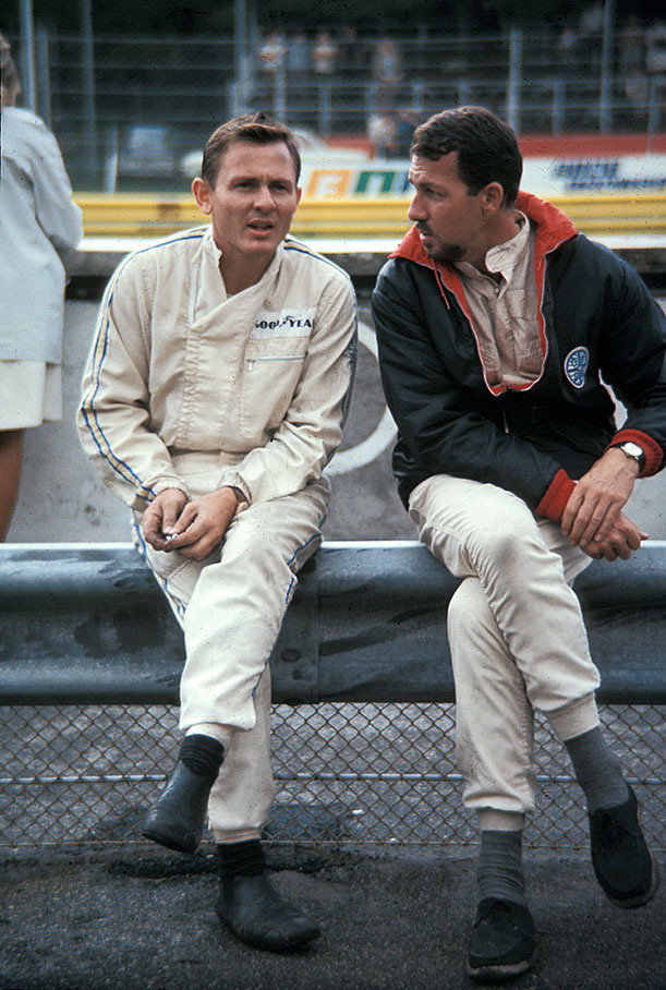 Bruce McLaren sits on a rail with Joakim Bonnier, Italian GP Monza 1967