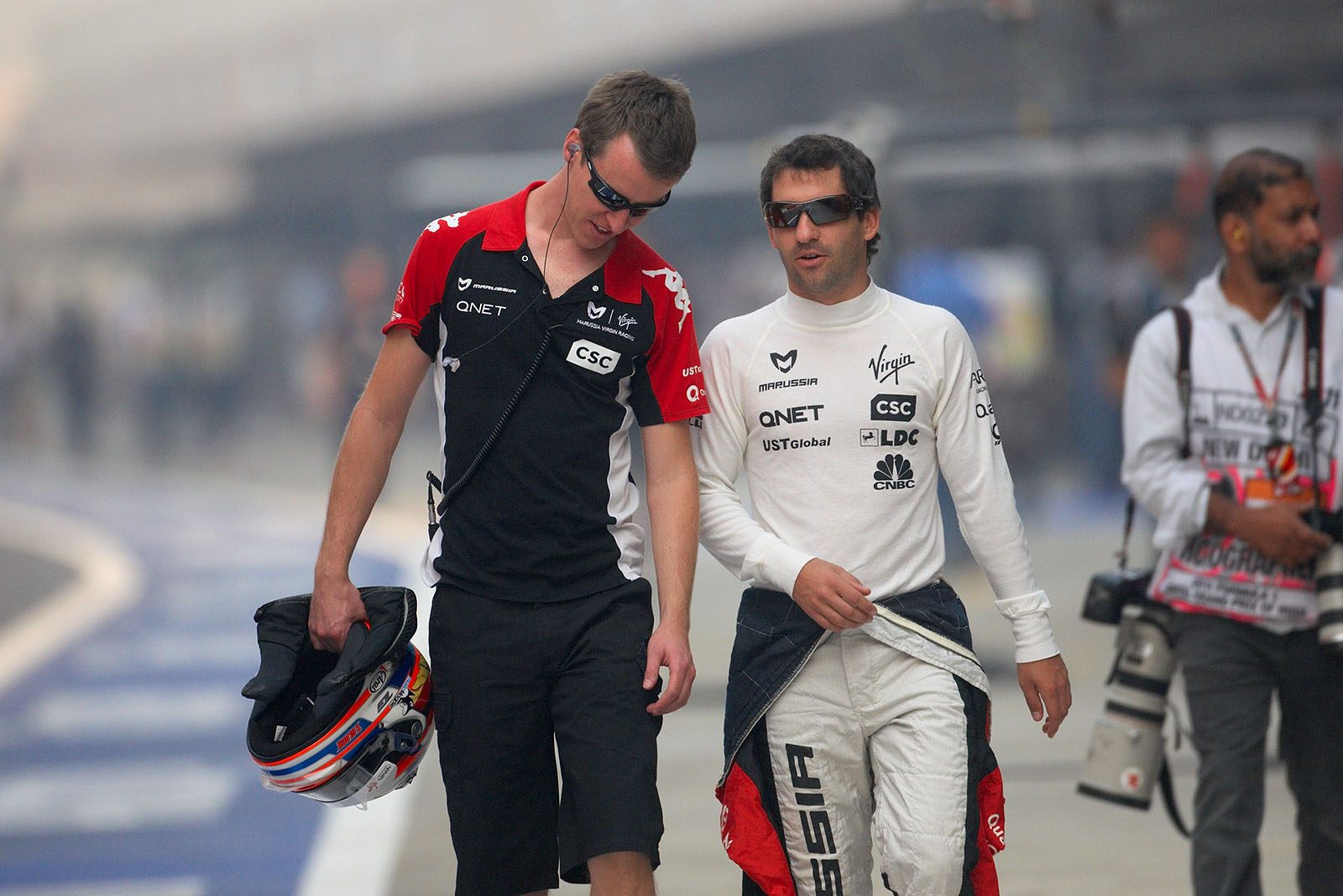 Virgin Racing's Timo Glock walks in the pitlane with his physio Axel Thielmann