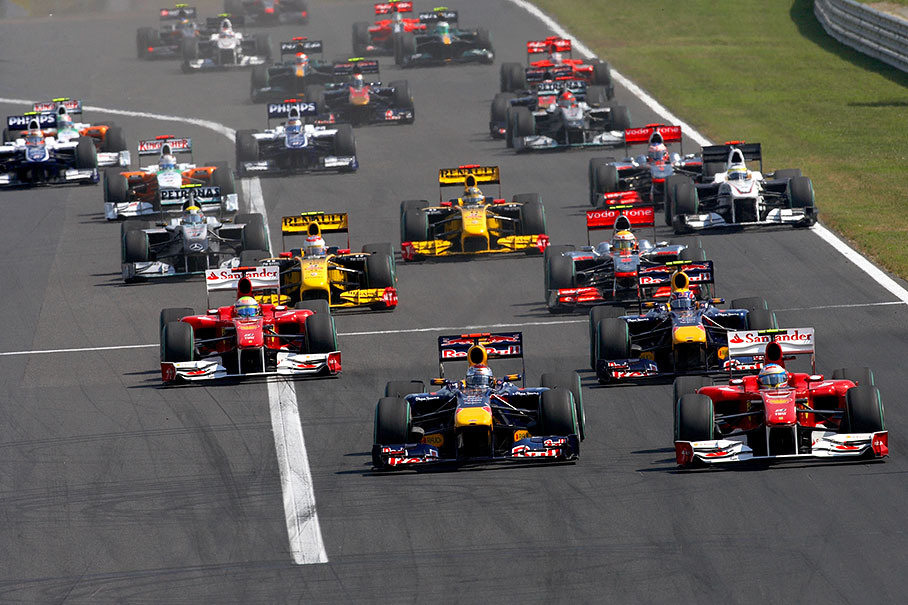 The start field approaches turn one, Vettel besides Alonso