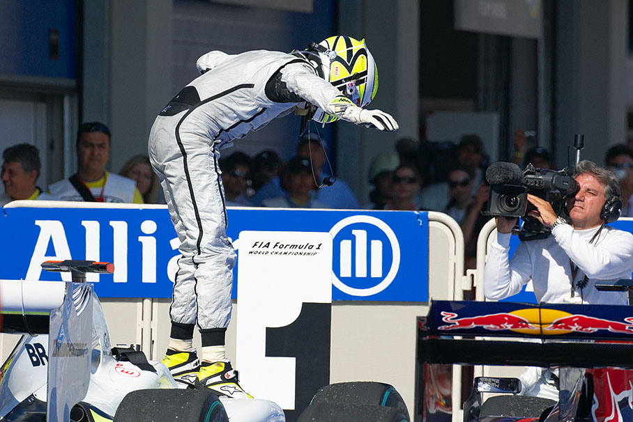 Race winner Jenson Button adjusts his balance after jumping on the Brawn GP car in parc ferme