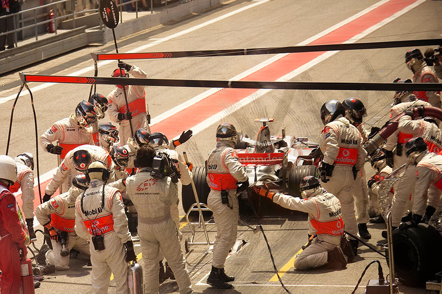 McLaren-Mercedes pit crew performs a service on Alonso's car