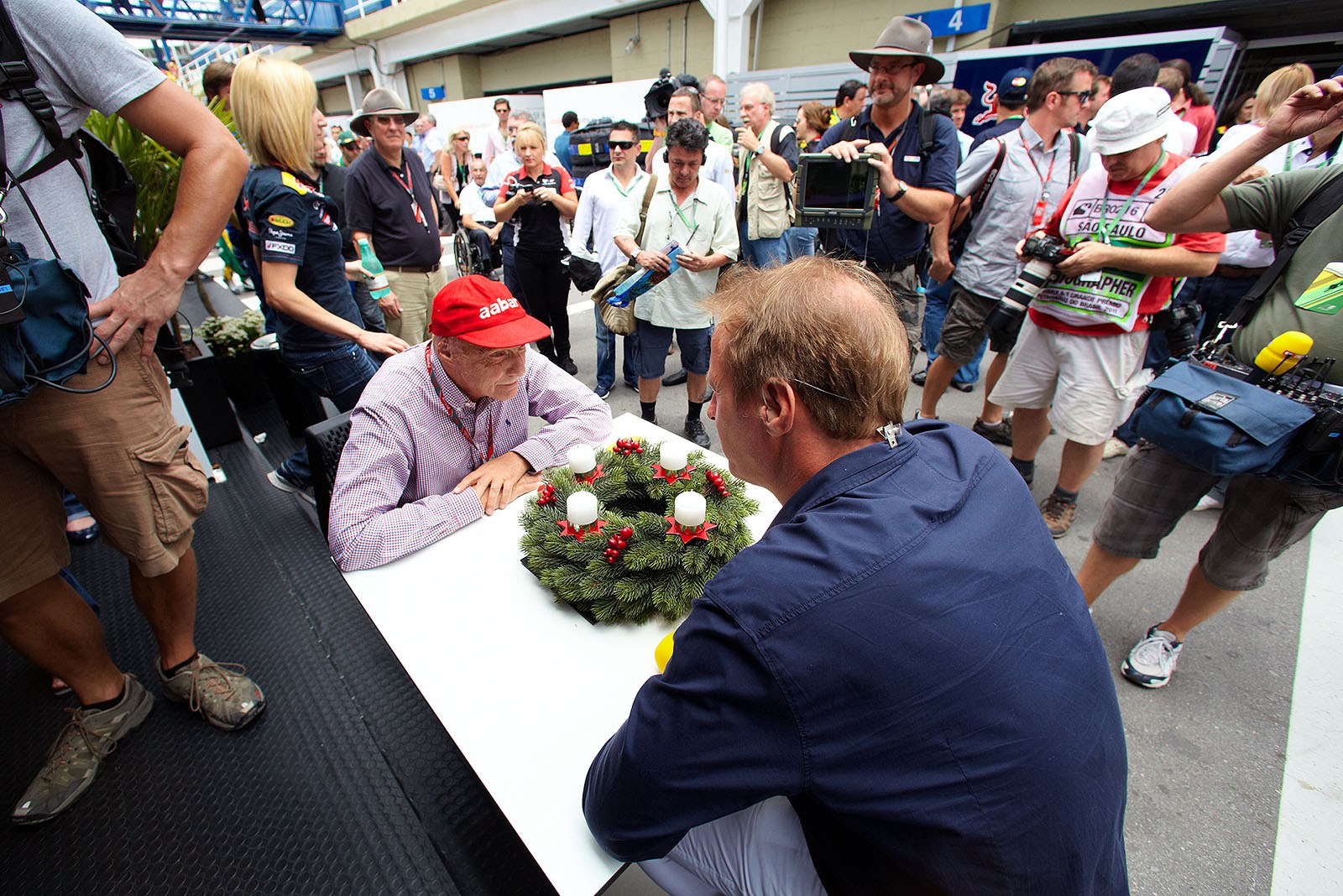 A crowded paddock with TV presenters Niki Lauda and Florian König in the middle, watched by countless journalists and bystanders