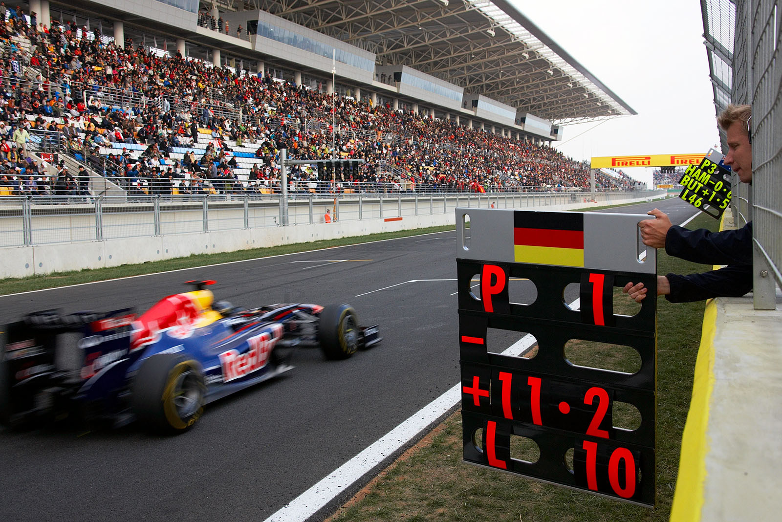 Tommi Parmakoski signals Sebastian Vettel, Red Bull Racing, P1 with 10 laps to go