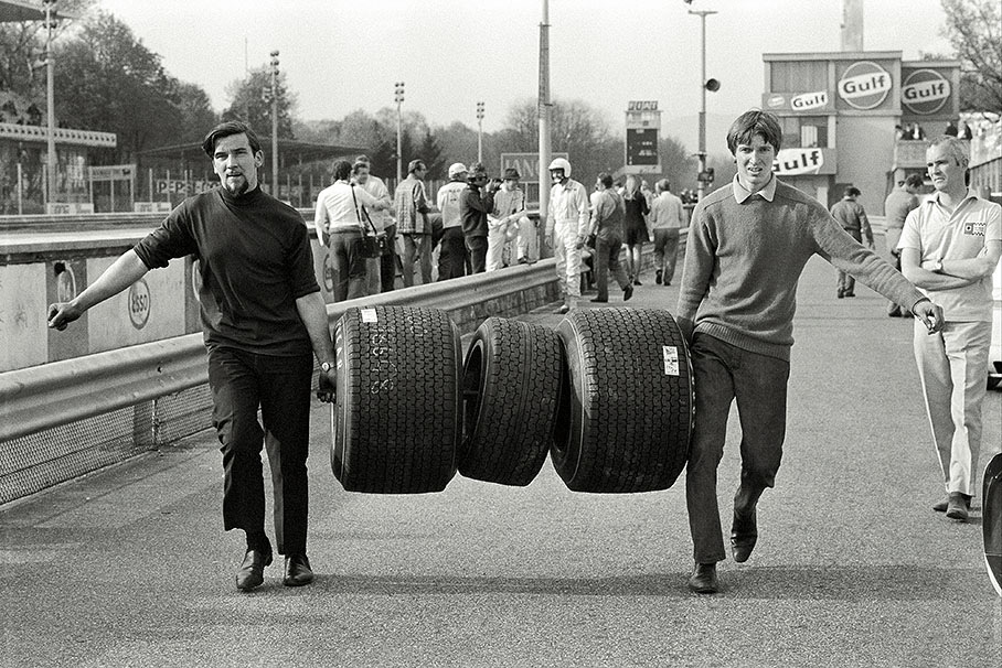 Two mechanics carry three tyres