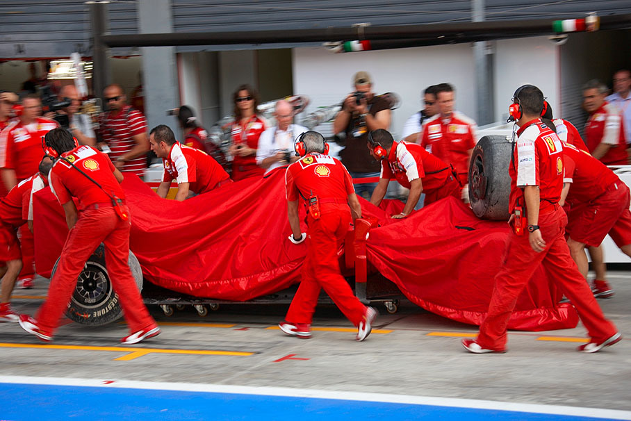 Fisichella's damaged Ferrari is being returned to pits after his adaption of the unfamiliar seat under pression results in a crash during the Saturday morning practice