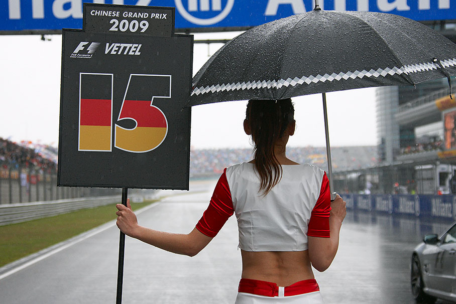Vettel's grid girl holds the number and an umbrella