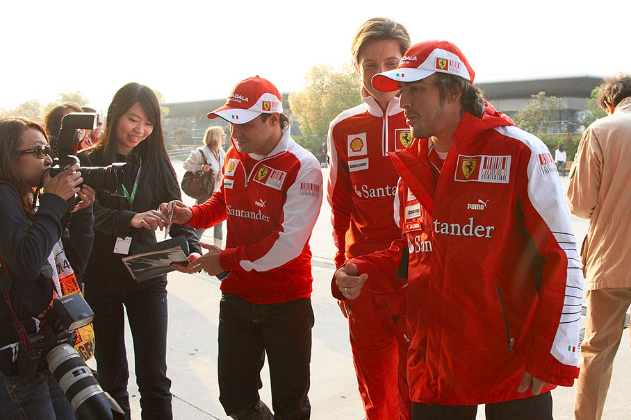 The Ferrari drivers are being chased by autograph hunters on their way to drivers meeting