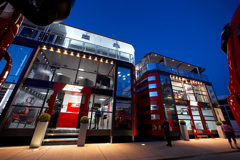 The two Ferrari motorhomes illuminate the paddock in the evening