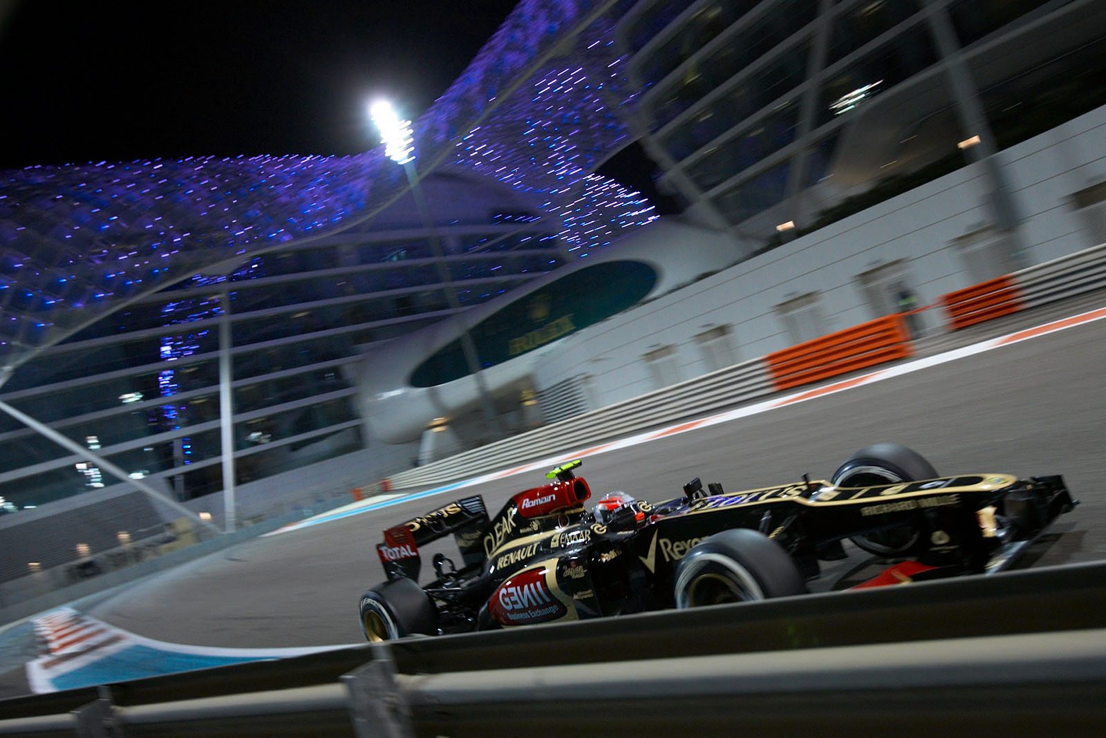 Romain Grosjean, Lotus-Renault, currently in 4th place, passes the Yas Viceroy Hotel. The hotel has two towers linked together by a bridge of monocoque steel and glass.
