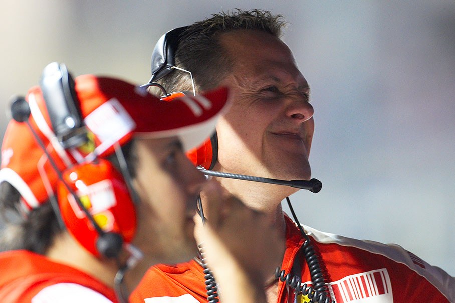 Michael Schumacher mugs behind Felipe Massa at Ferrari's pit wall command center
