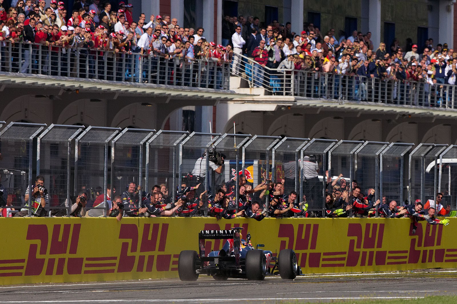 Sebastian Vettel passes his cheering Red Bull Racing team, winning his fourth GP out of five so far this season